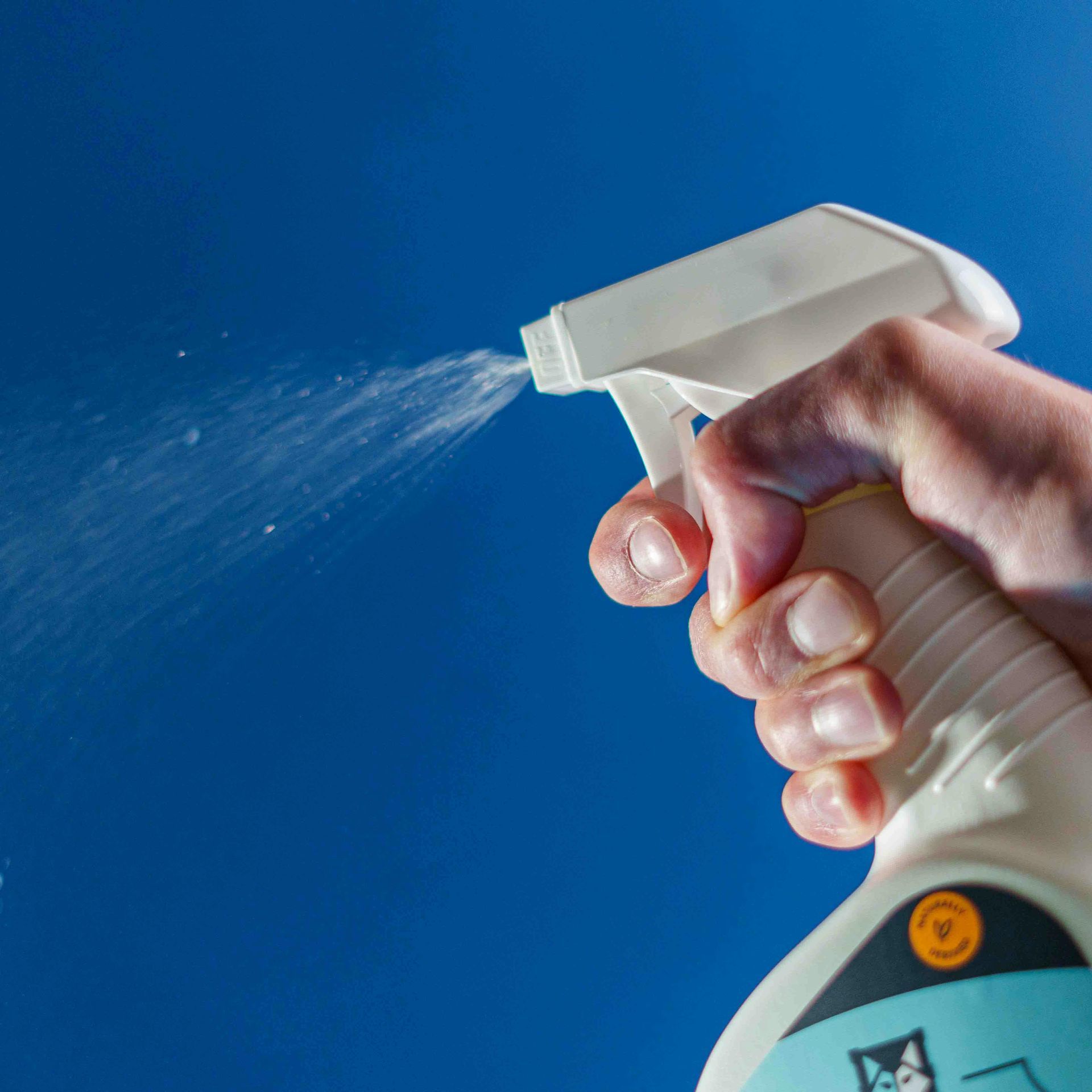 A person is holding a spray bottle with a cat on it