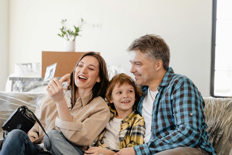 A family is sitting on a couch looking at a tablet.