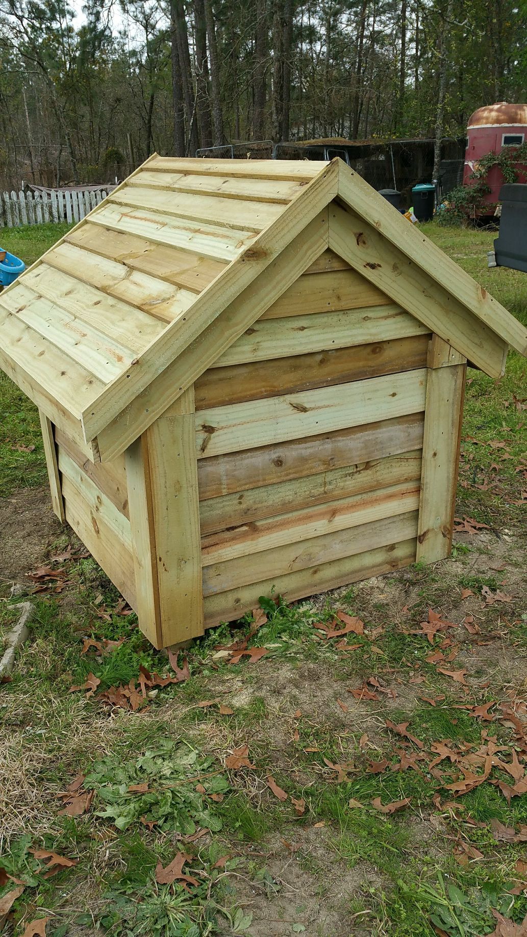 A small wooden dog house is sitting on top of a lush green field.