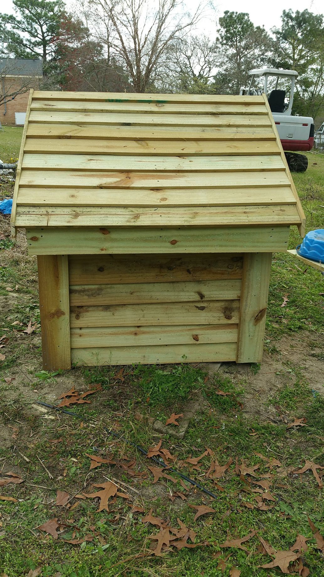 A small wooden dog house is sitting on top of a lush green field.