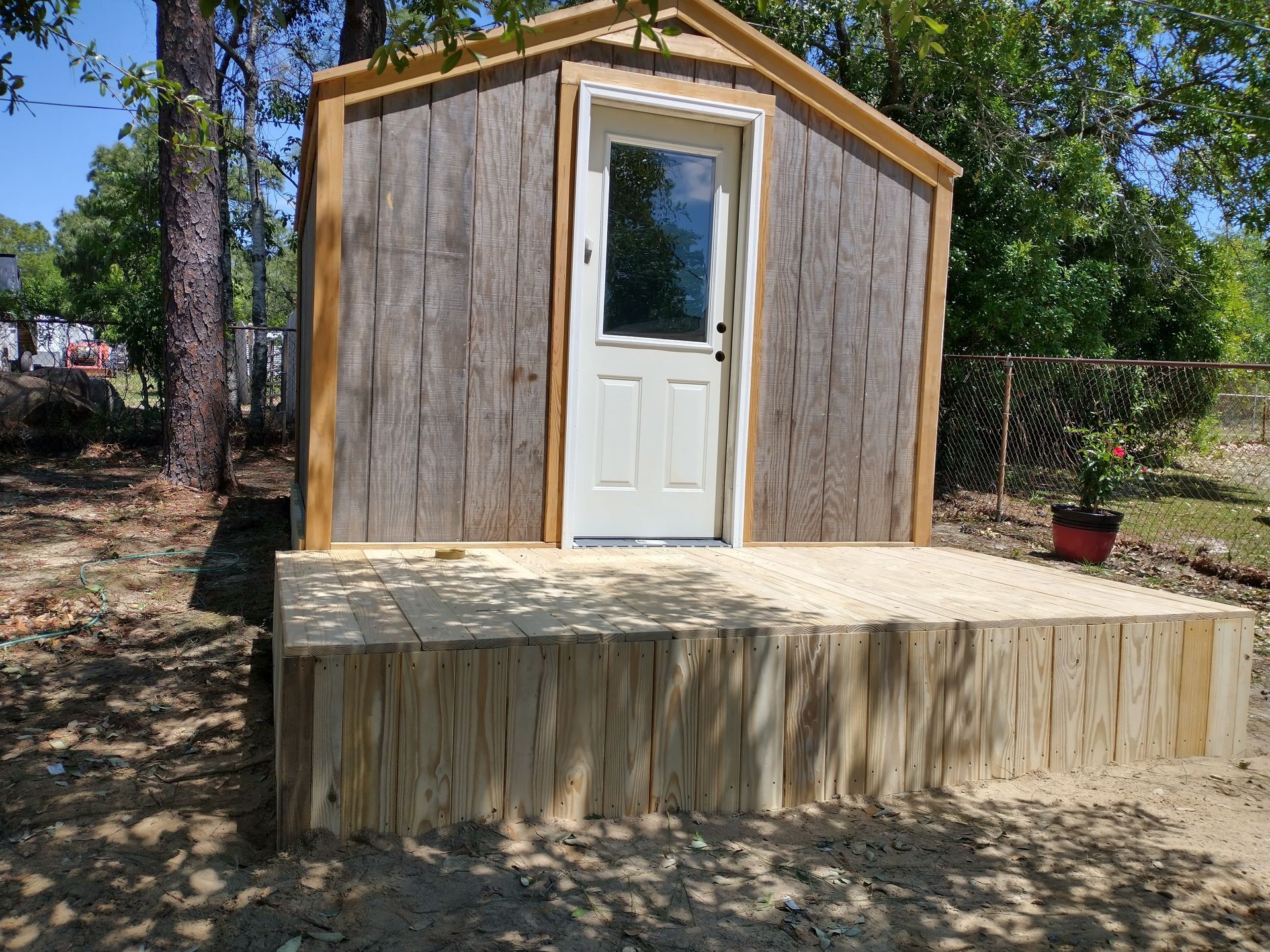 A small wooden shed with a white door and window