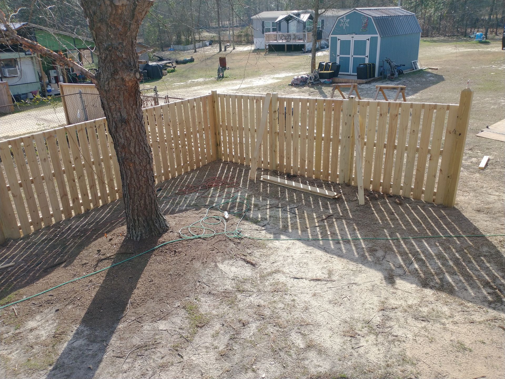 A wooden fence is surrounding a tree in a yard.