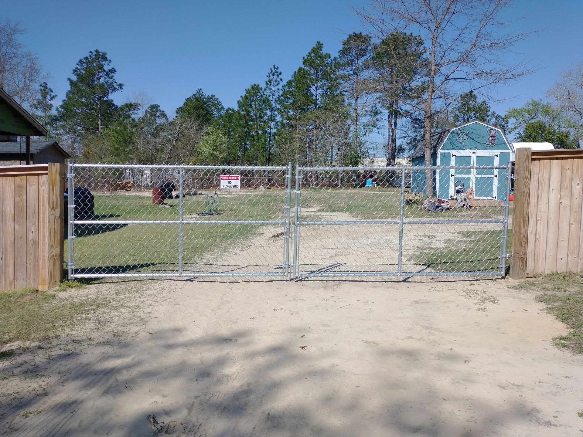 A chain link gate is open to a dirt road