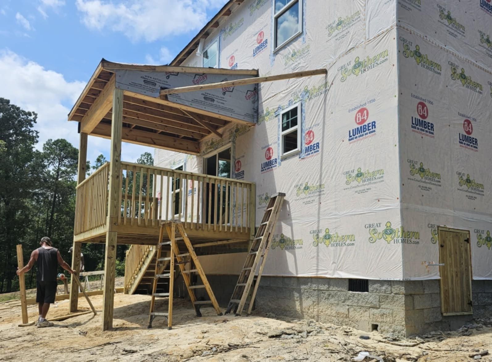 A man is walking towards a house under construction with a wooden deck.