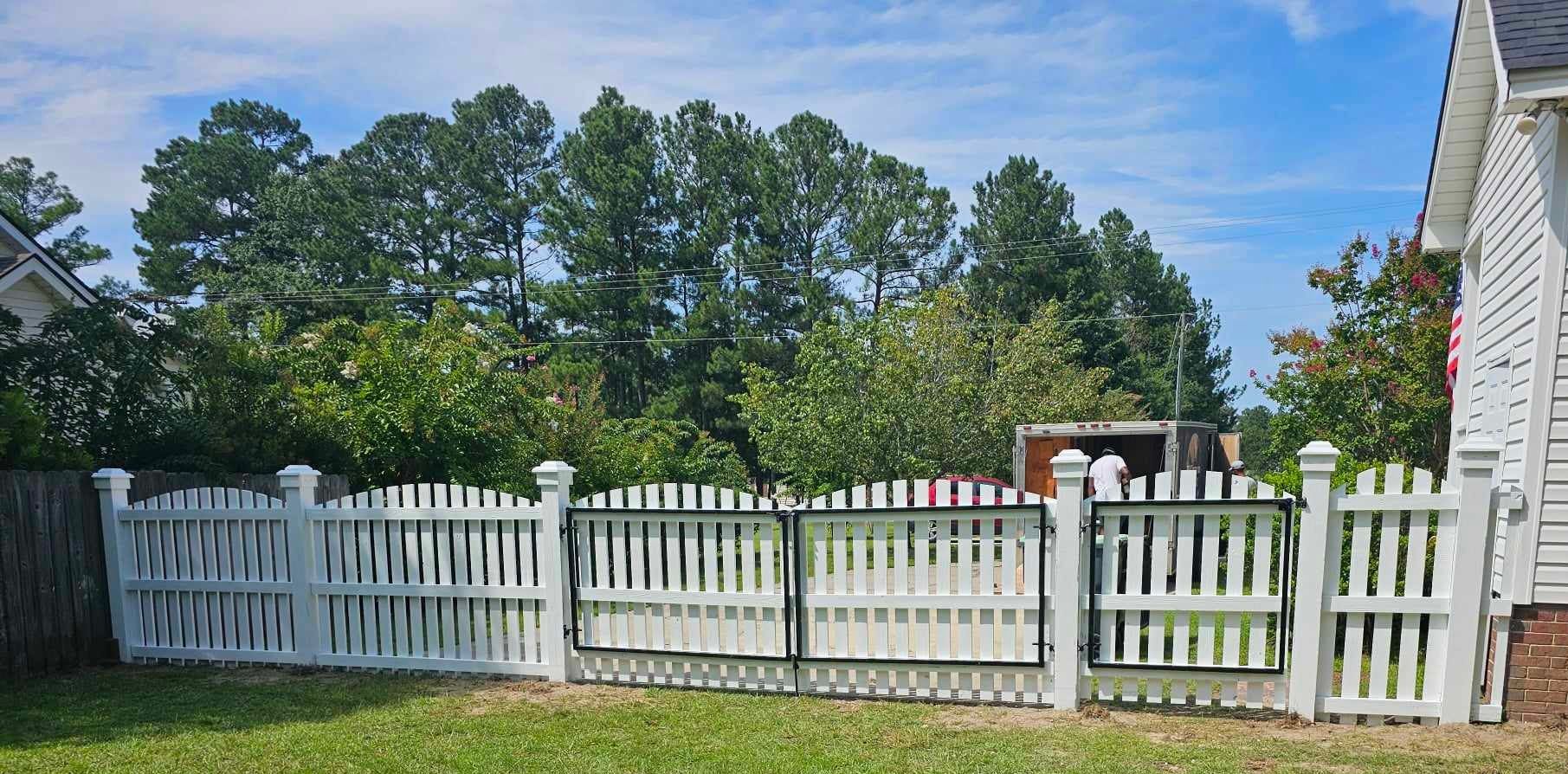 A white picket fence with a gate in front of a house.