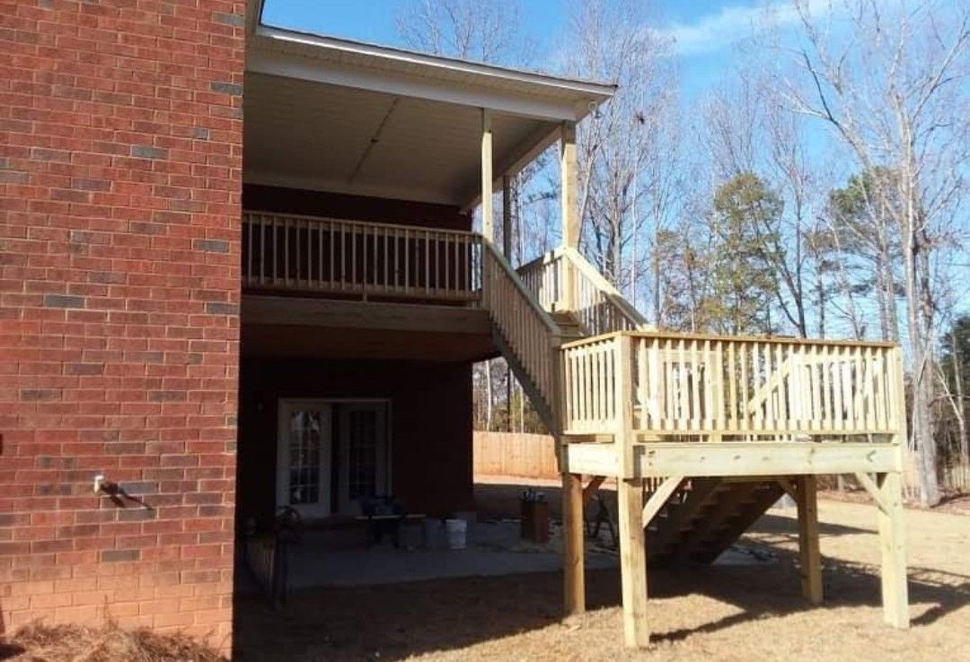 A brick house with a wooden deck and stairs.