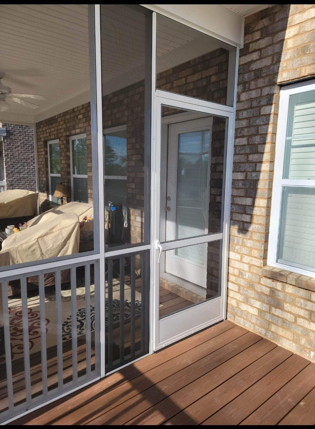 A screened in porch with a brick building in the background
