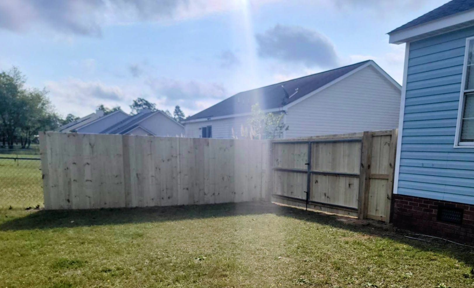 A wooden fence is in the backyard of a house.