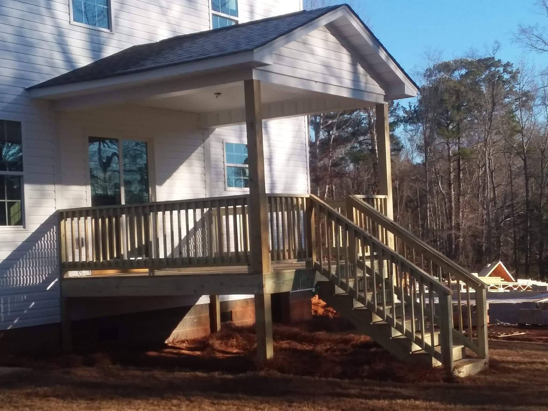 A white house with a wooden deck and stairs