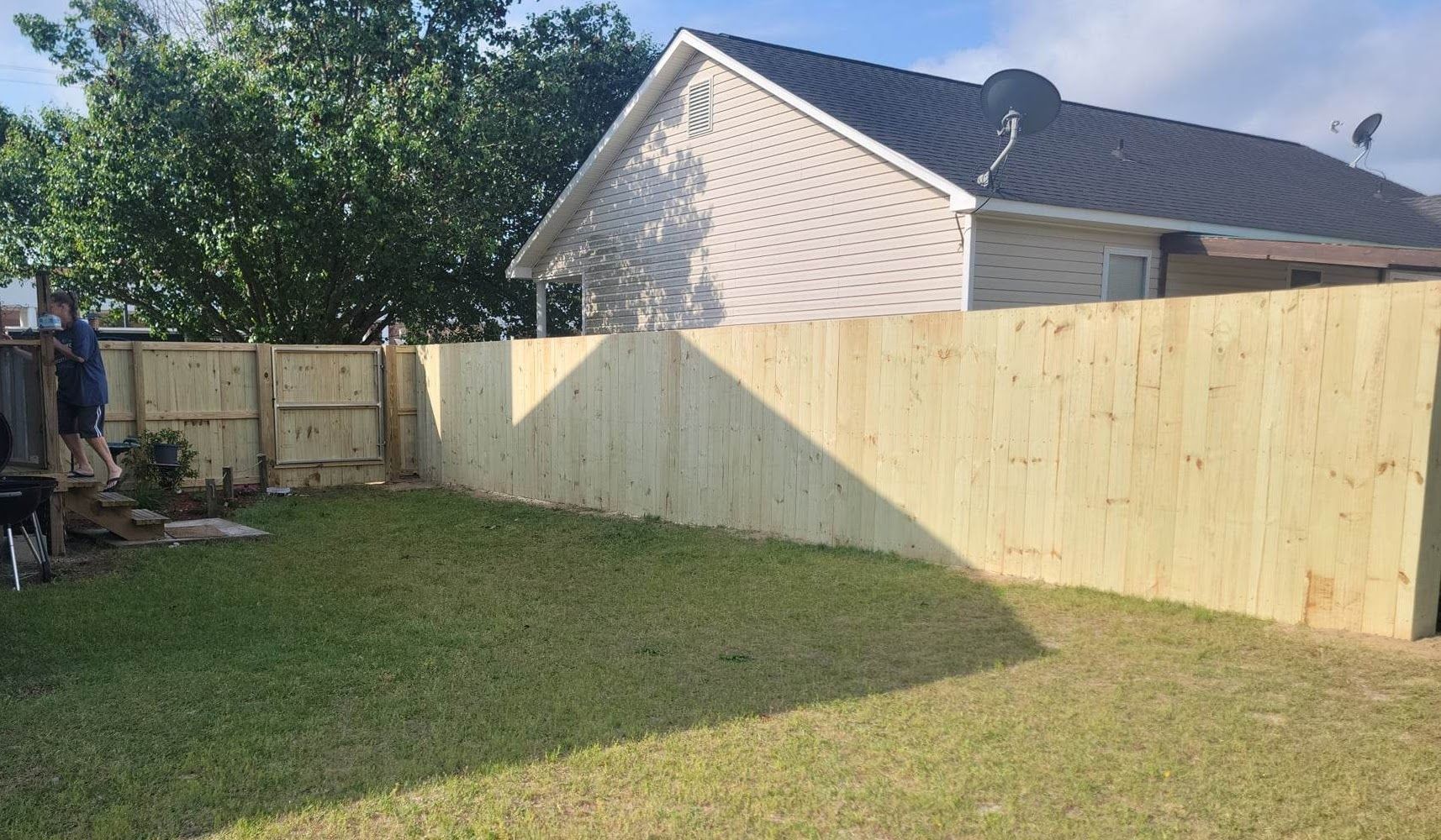 A wooden fence is in the backyard of a house.