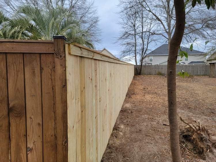 A wooden fence in a backyard with a house in the background.