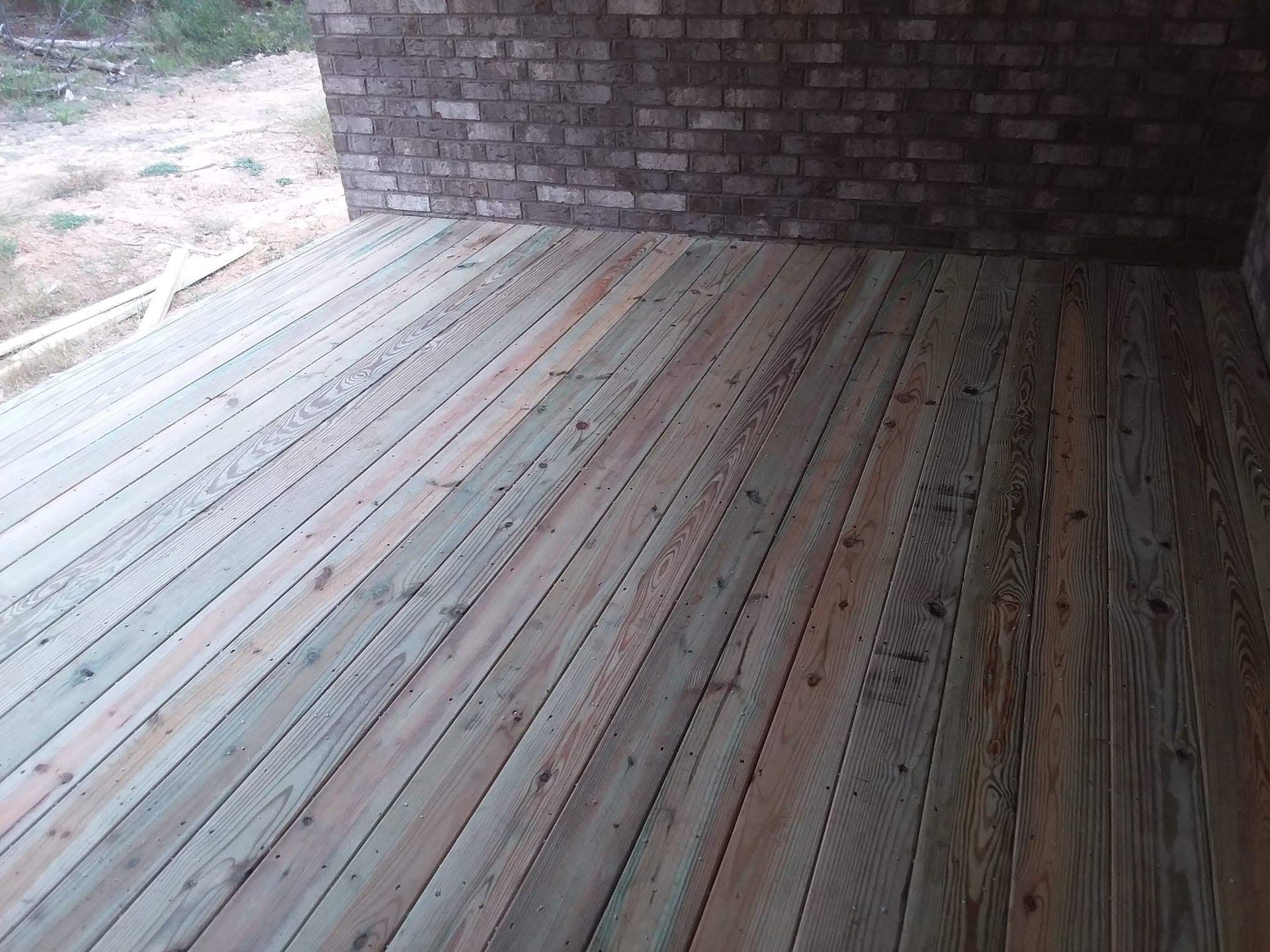 A wooden deck with a brick wall in the background
