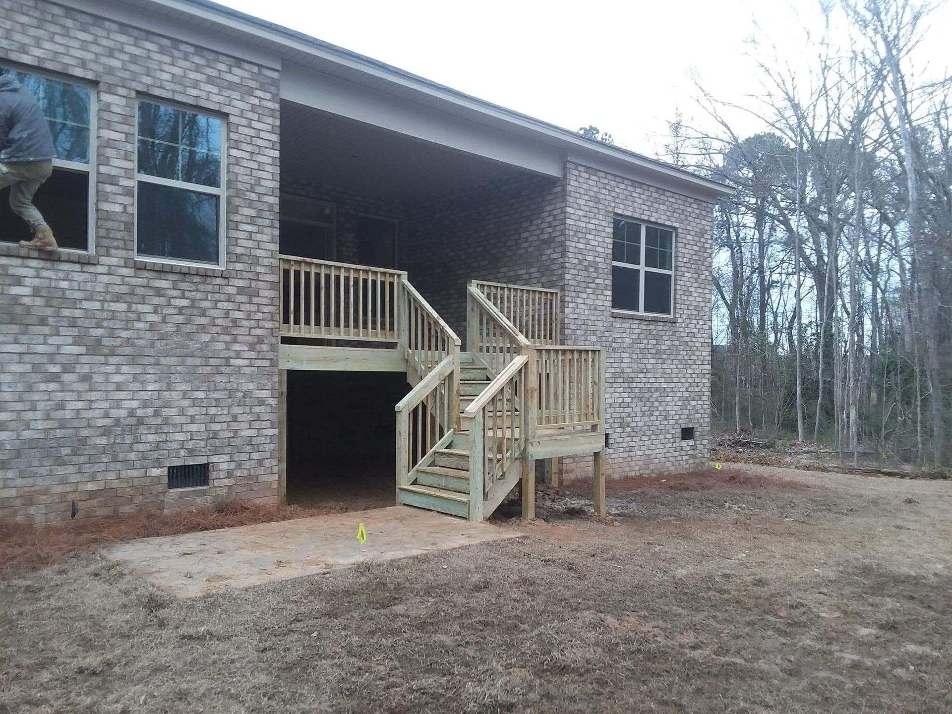 A brick house with a wooden deck and stairs in front of it.