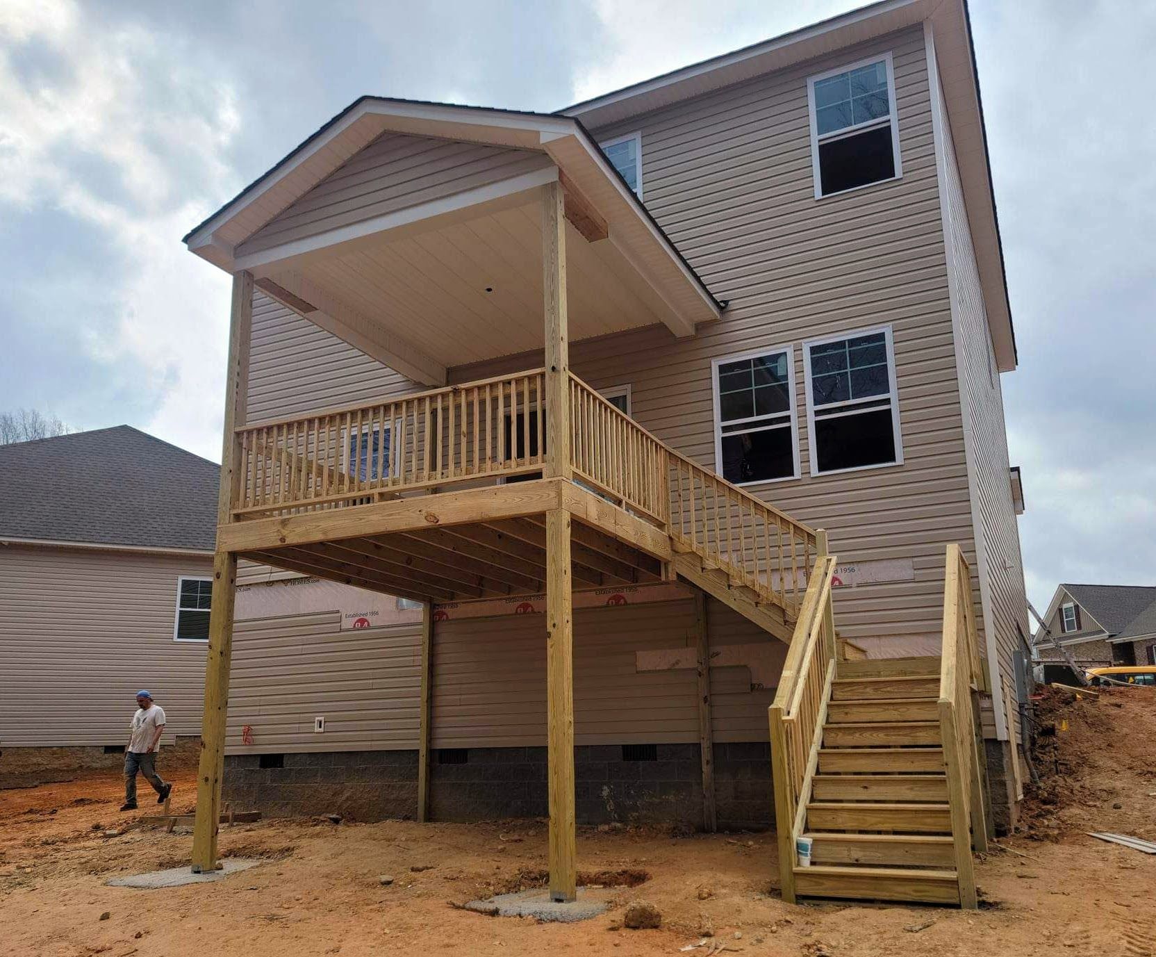 The back of a house with a wooden deck and stairs.