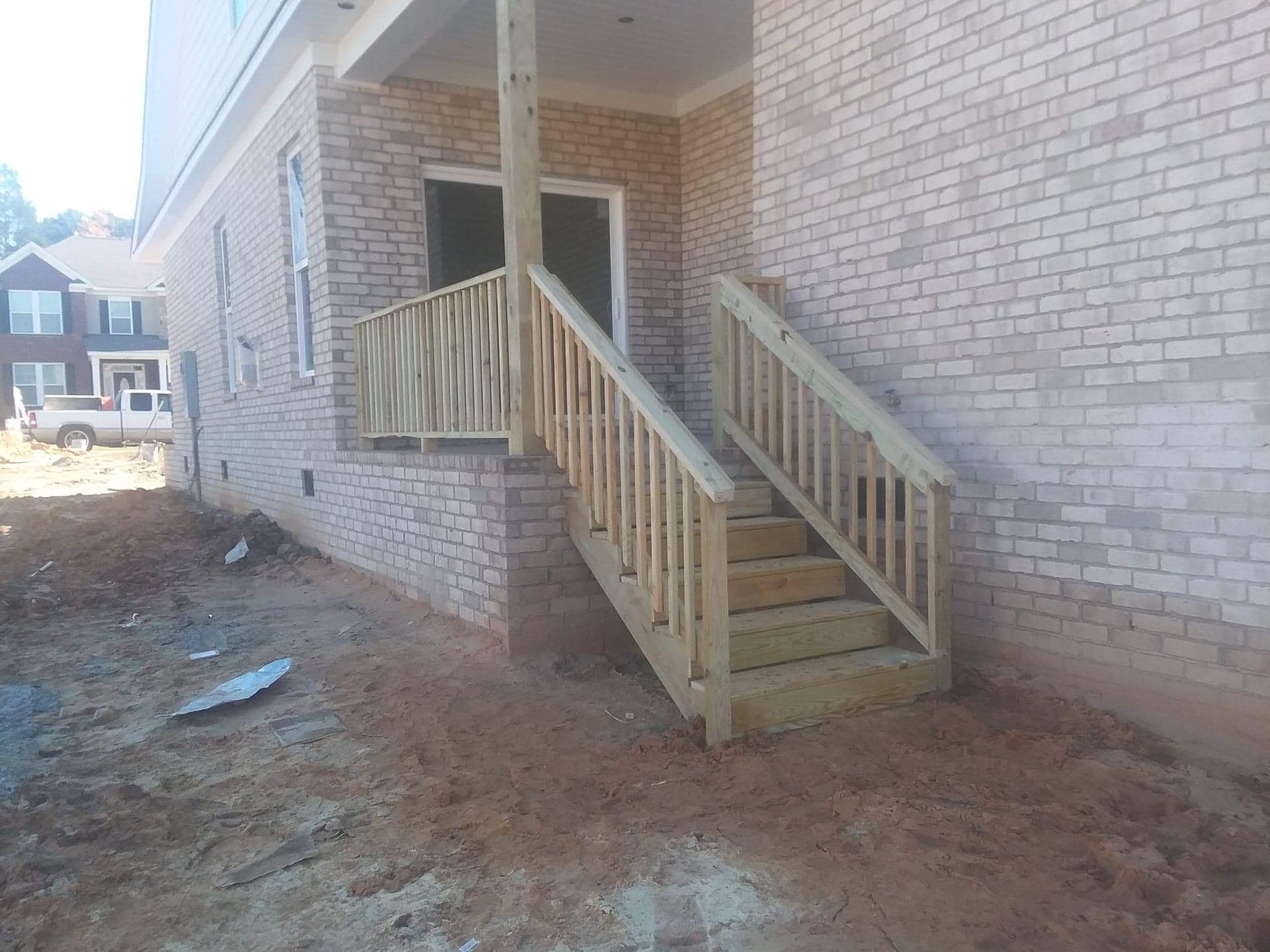 A wooden deck with stairs leading up to a brick building.