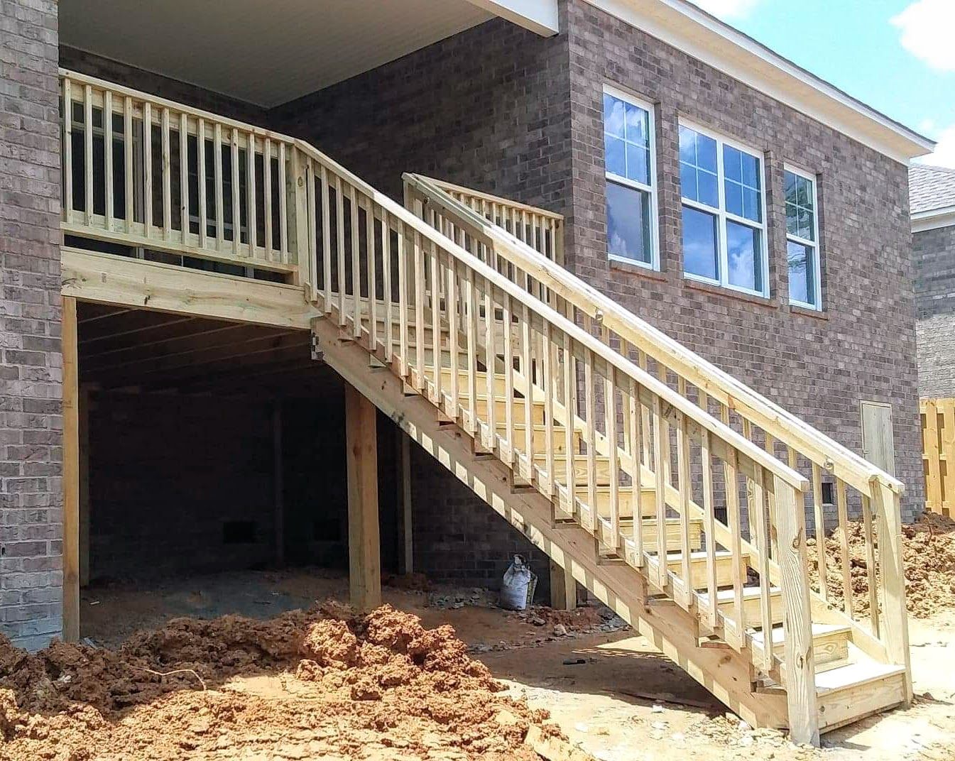 A wooden deck with stairs leading up to a brick house