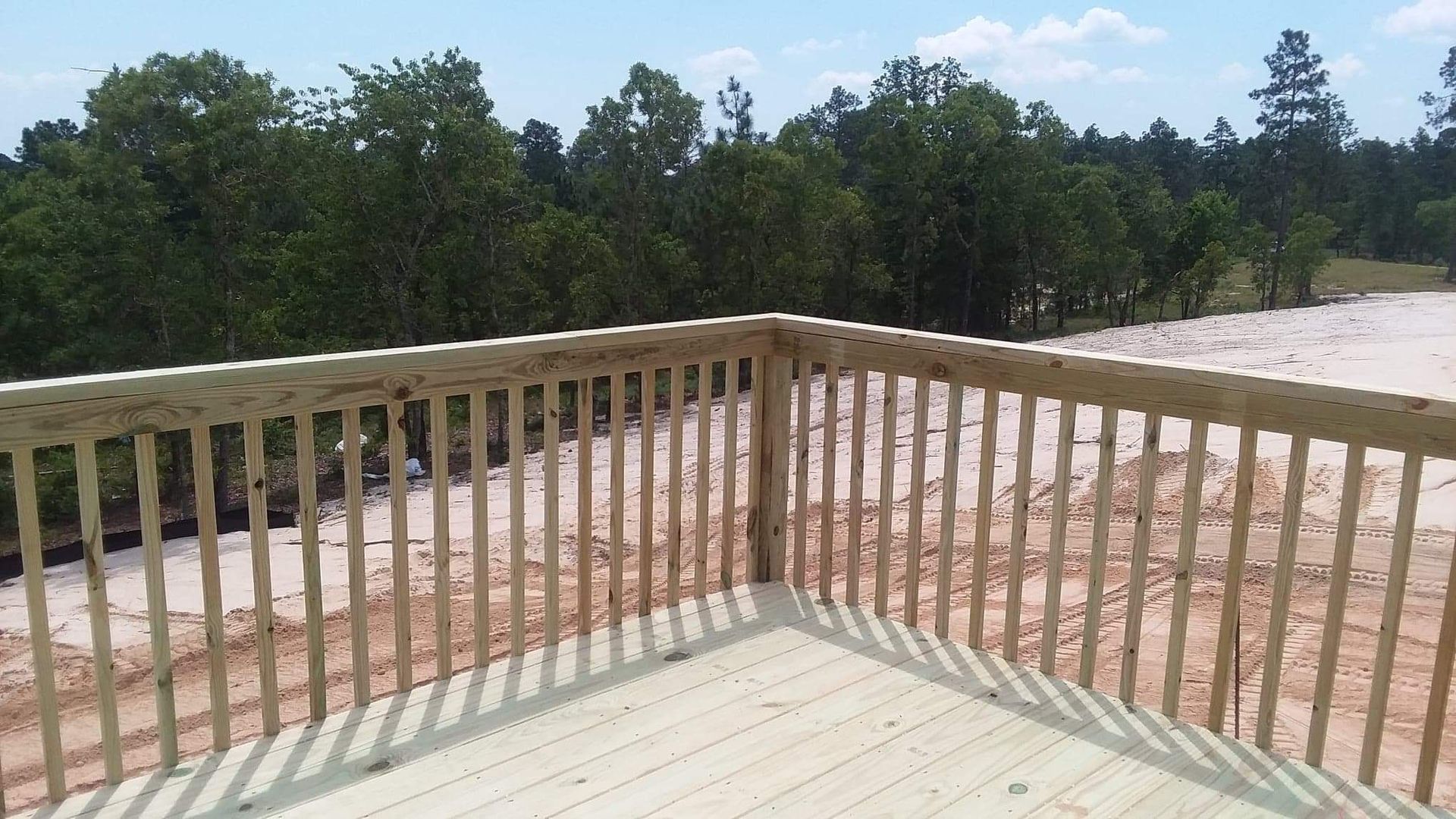 A wooden deck with a railing and trees in the background