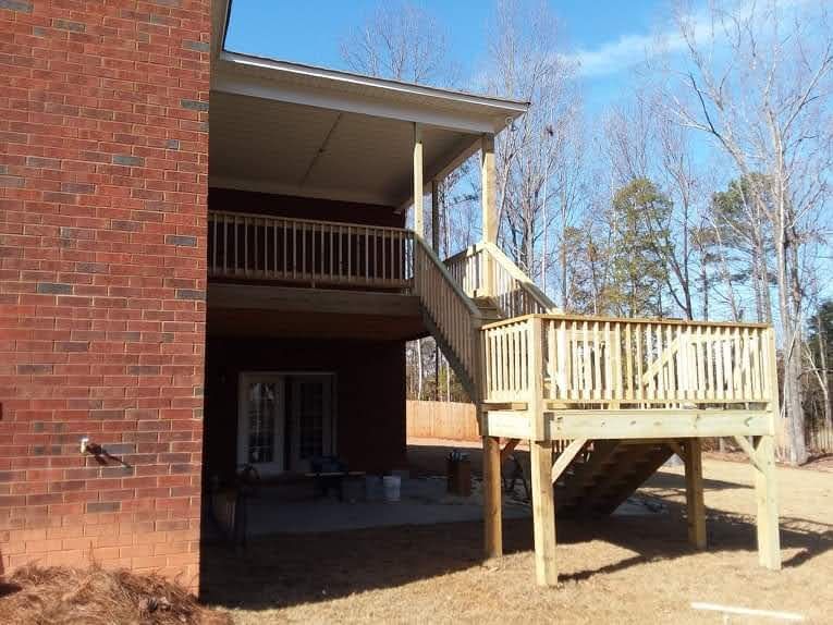 A brick house with a wooden deck and stairs.