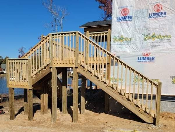 A wooden deck with stairs and a lumber sign in the background