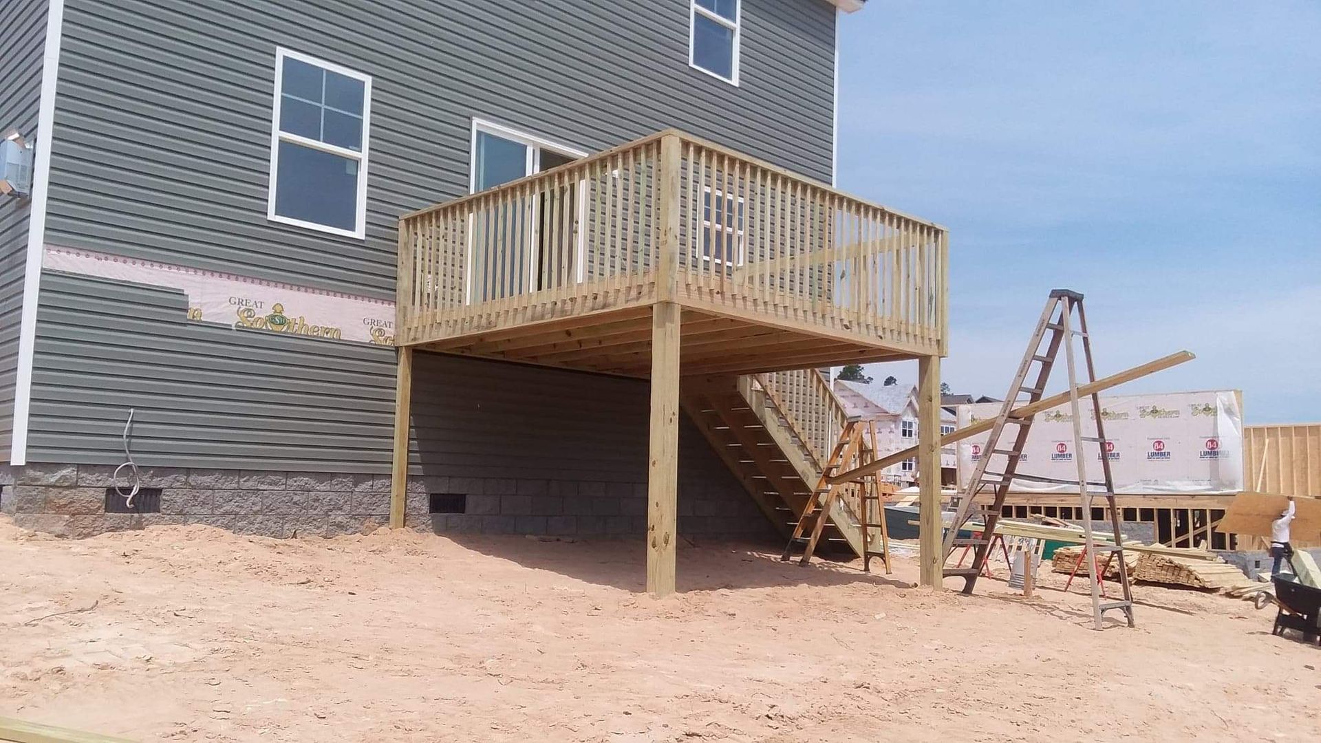 A wooden deck is being built in front of a house.
