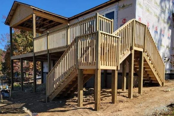 A wooden deck with stairs leading up to a house under construction.