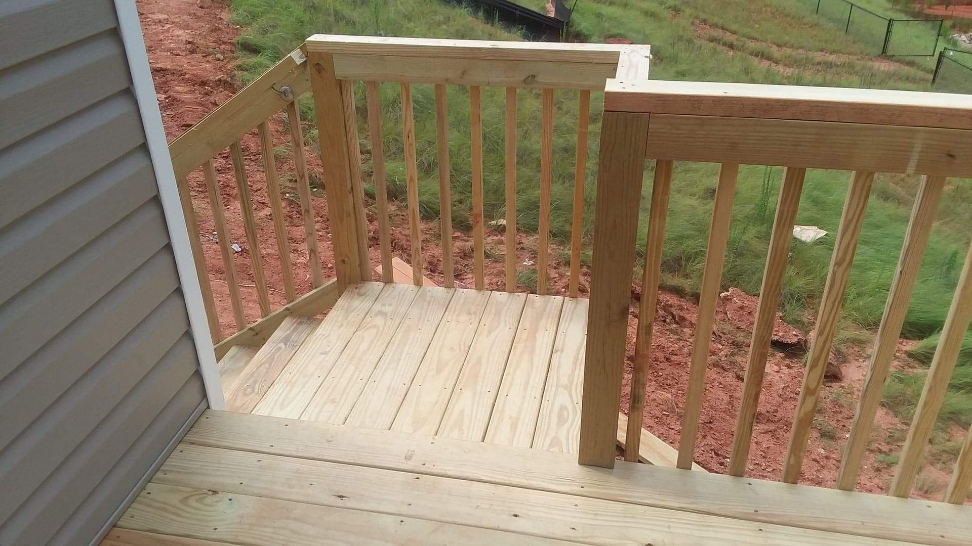 A wooden deck with stairs leading up to it next to a house.