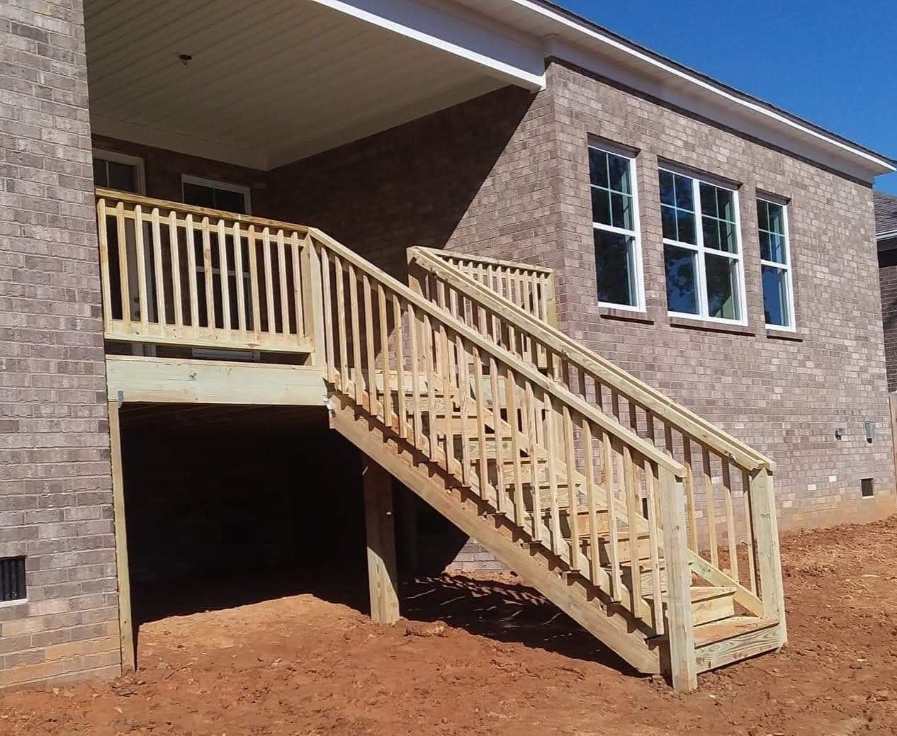 A brick house with a wooden deck and stairs