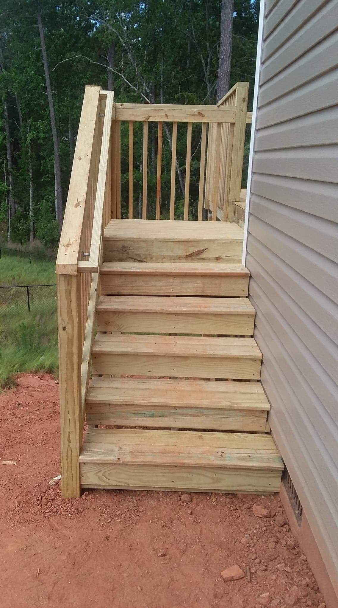 A wooden deck with stairs leading up to it next to a house.