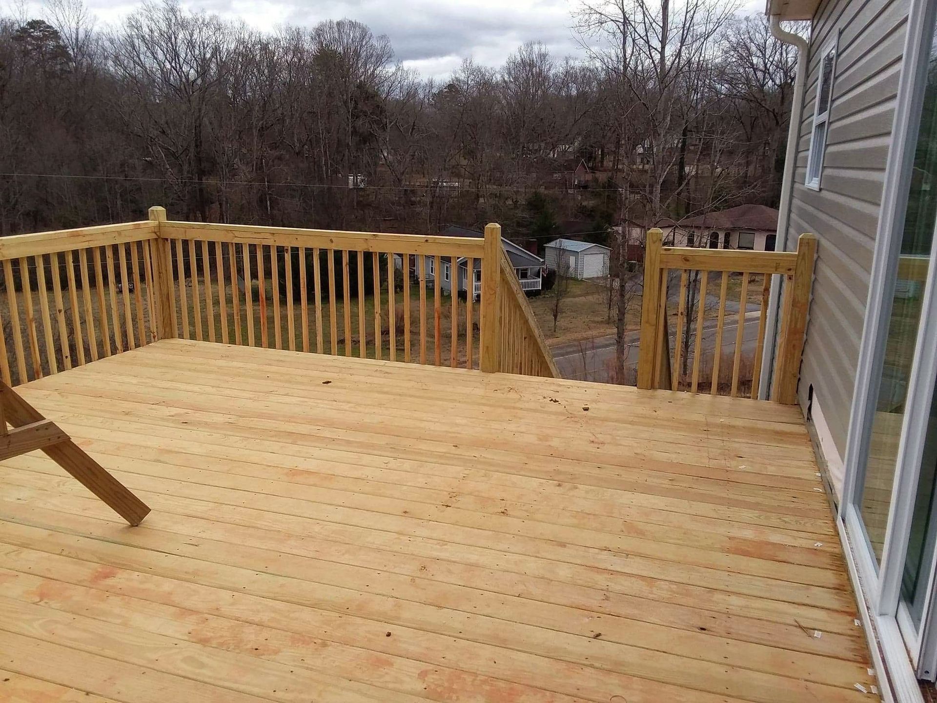 A wooden deck with a wooden railing and stairs leading up to it.