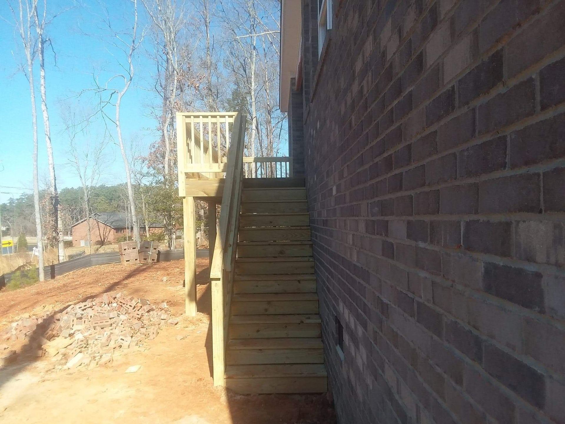 A wooden deck is attached to the side of a brick building.