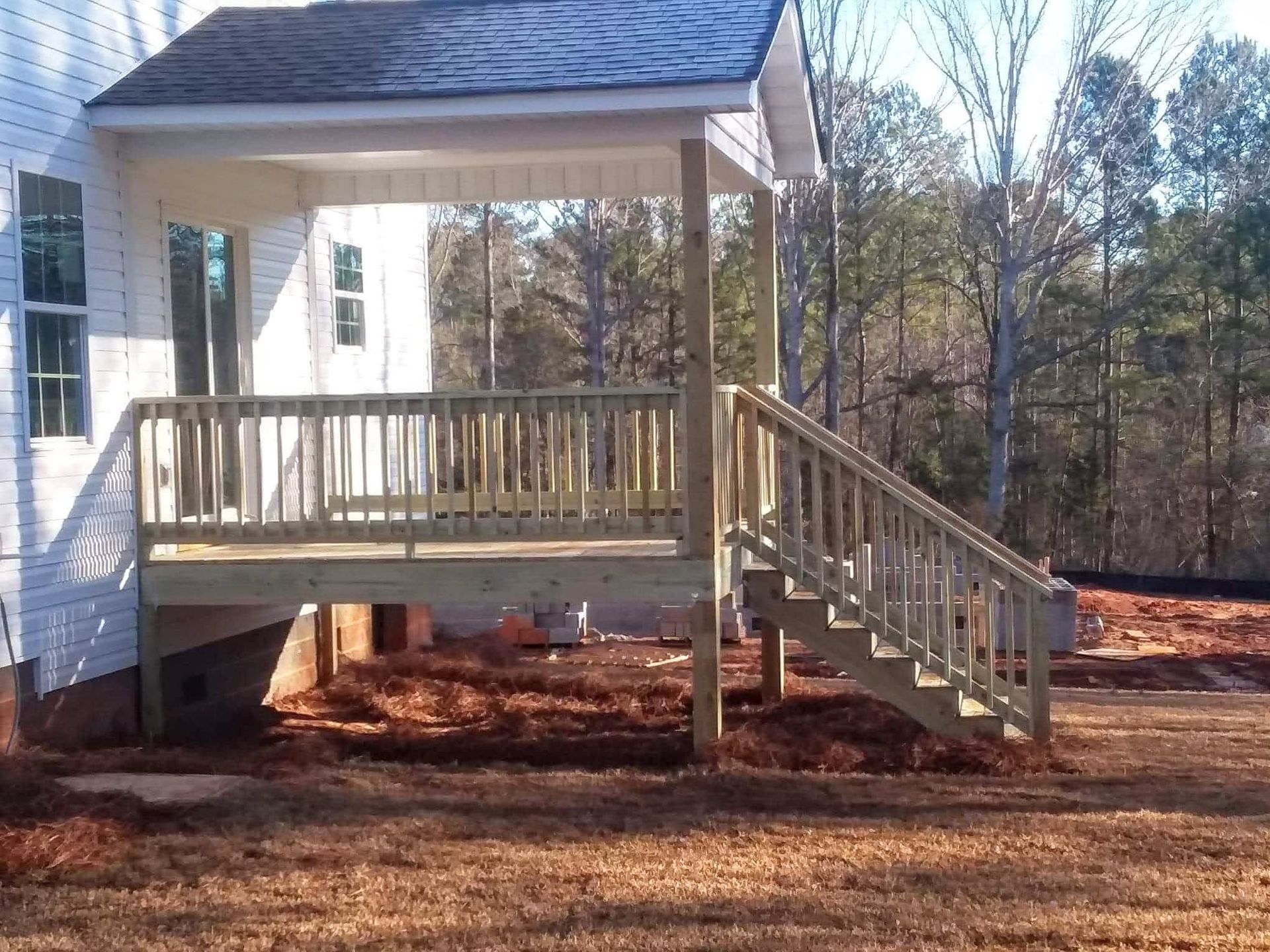 A white house with a wooden deck and stairs
