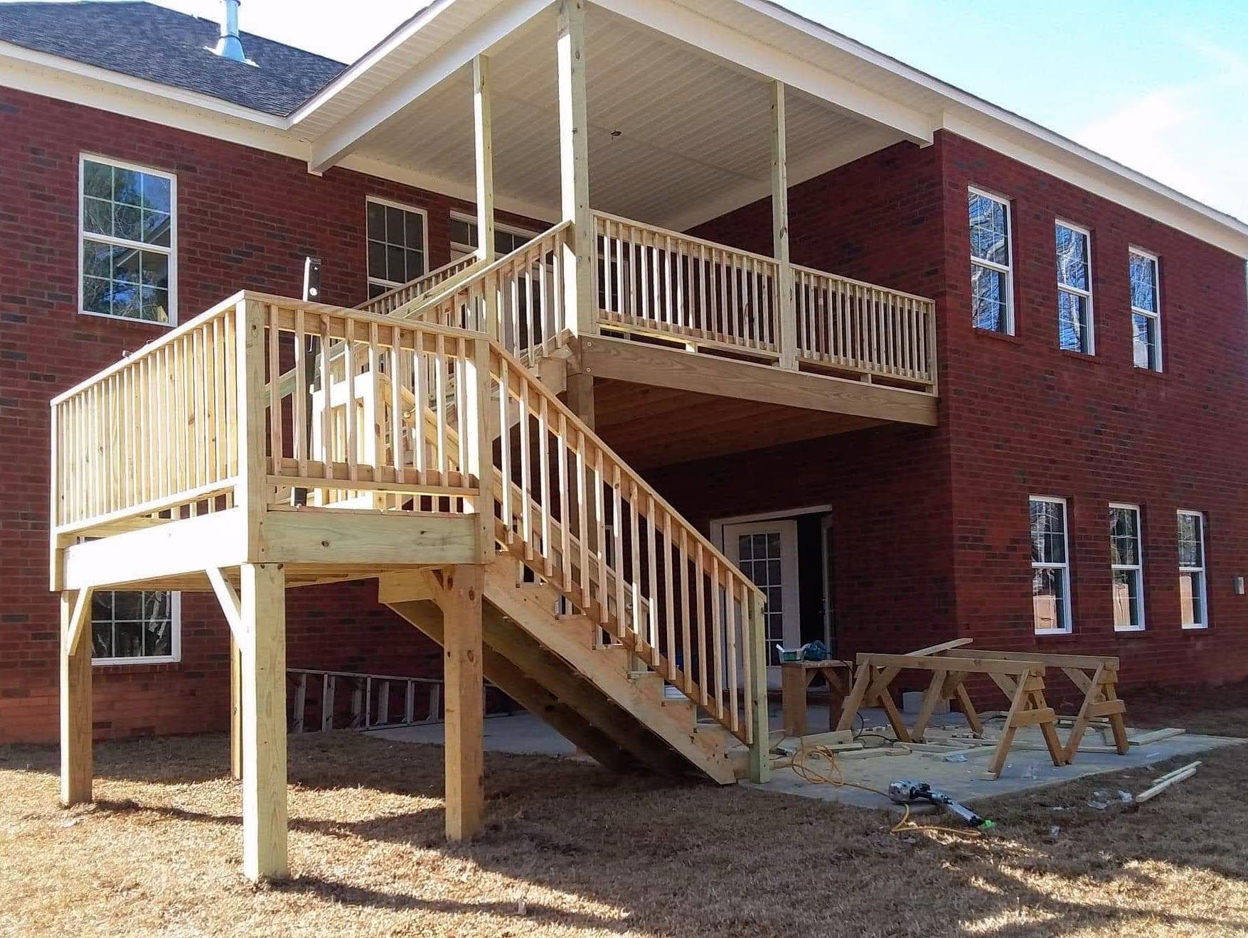 A large brick house with a wooden deck and stairs