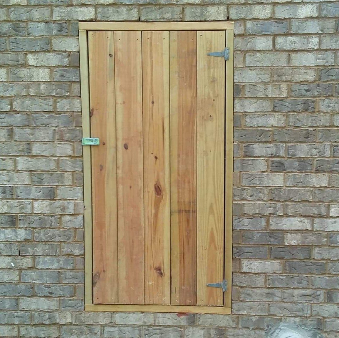 A wooden door is attached to a brick wall