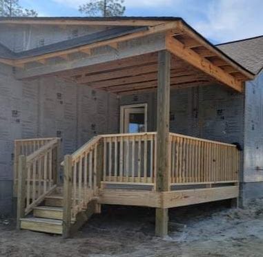 A wooden deck with stairs leading up to it is under construction.