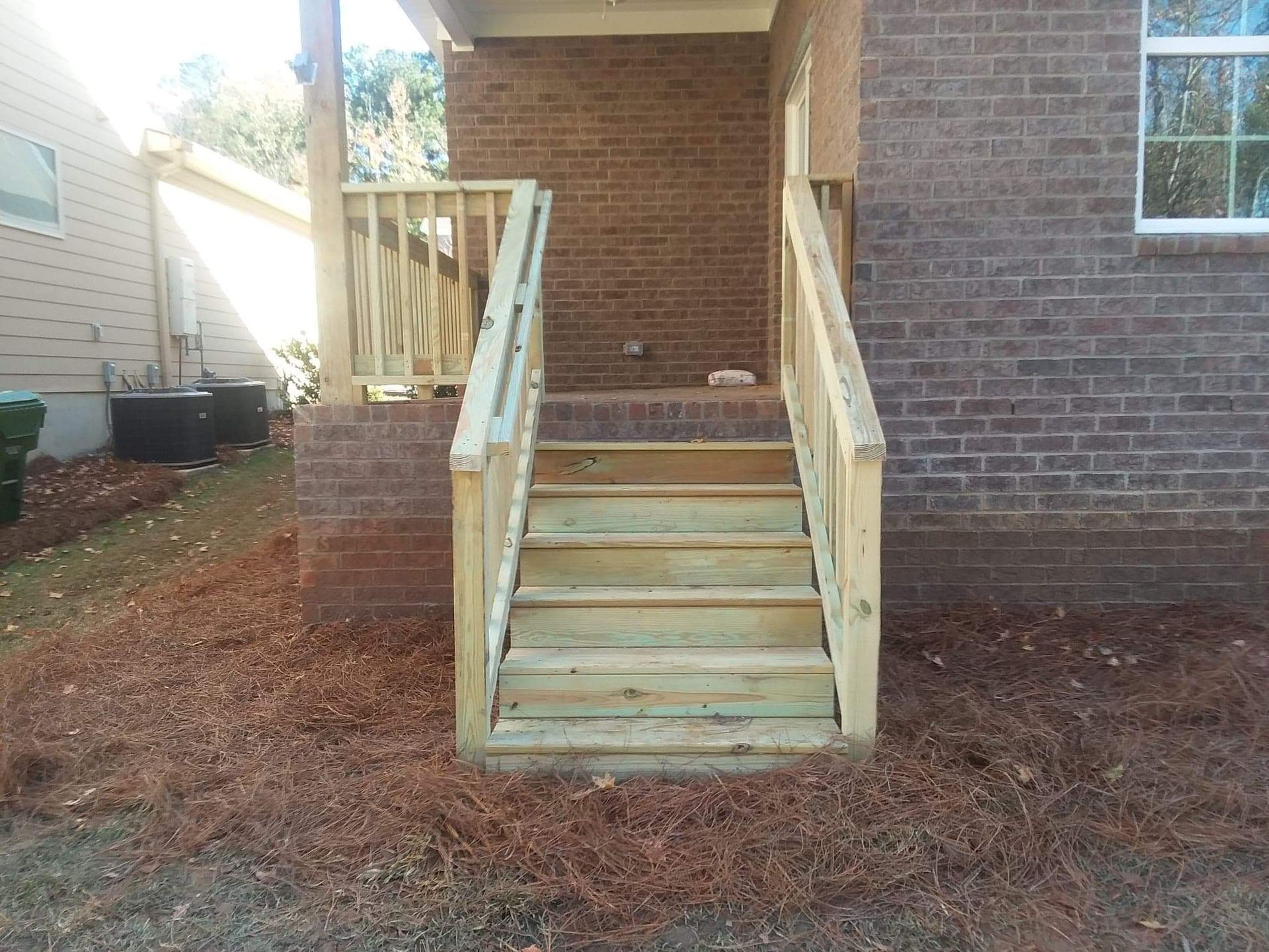 A wooden deck with stairs leading up to a brick house