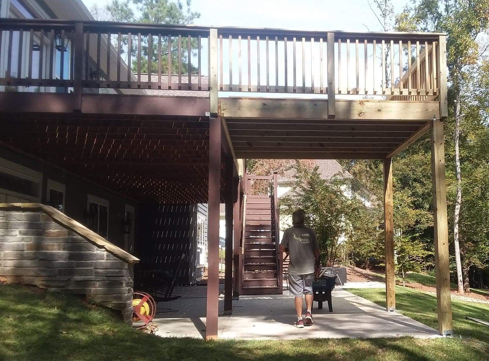 A man is walking under a deck with stairs