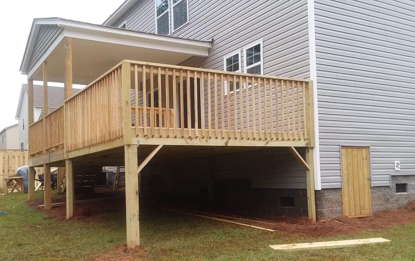 A large wooden deck is underneath a house