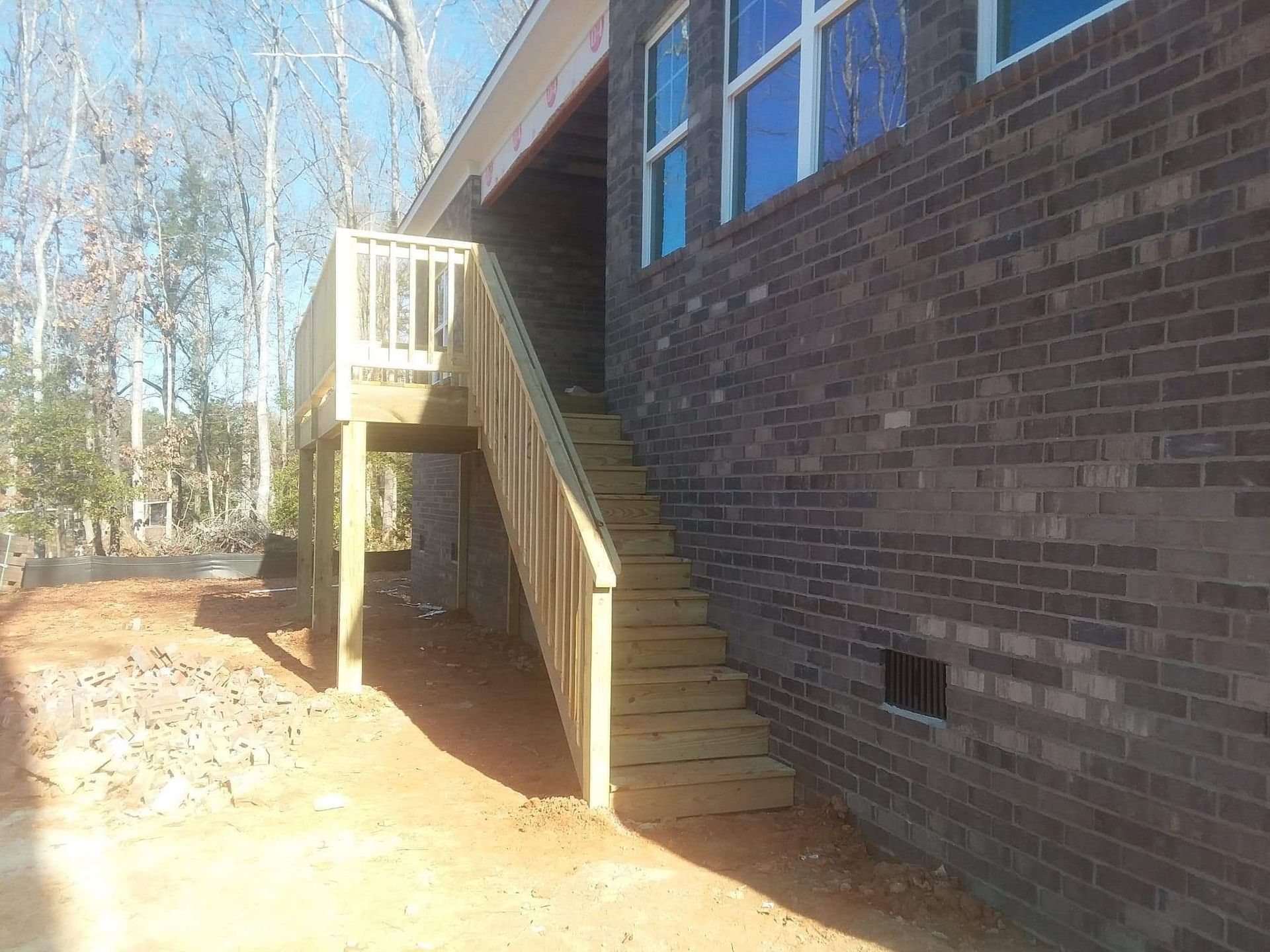 A wooden deck with stairs leading up to a brick building.