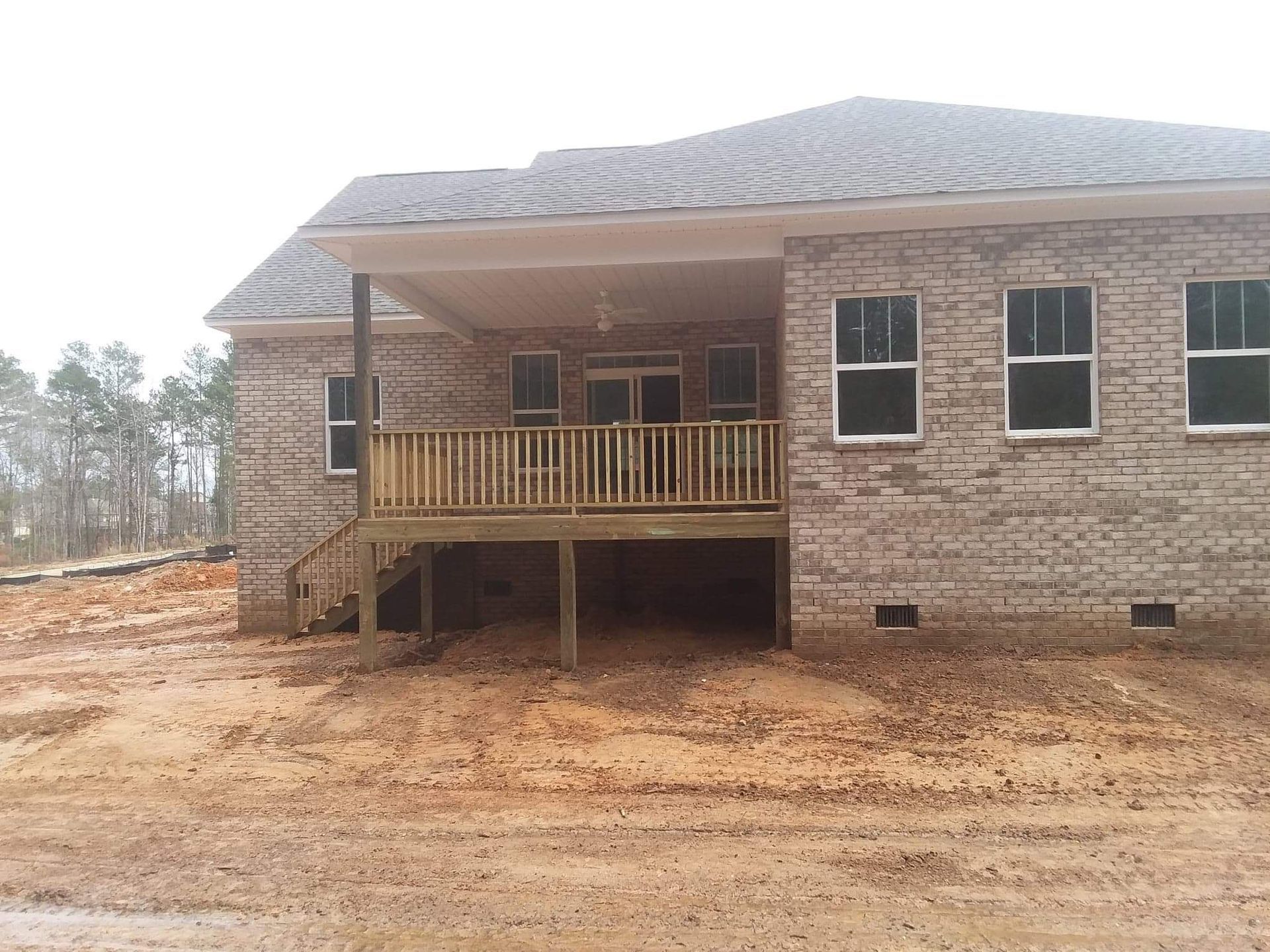 A brick house with a wooden deck in front of it.