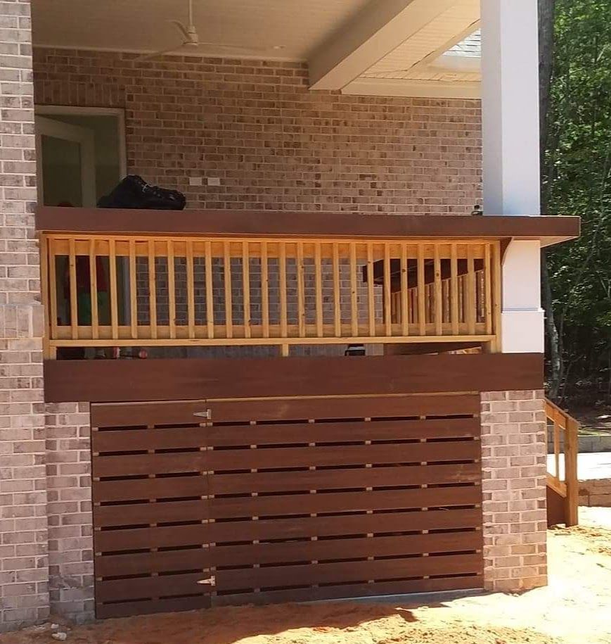 A brick house with a wooden railing on the porch