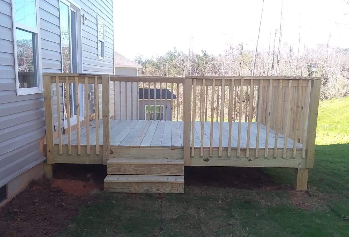 A wooden deck with stairs is in the backyard of a house.