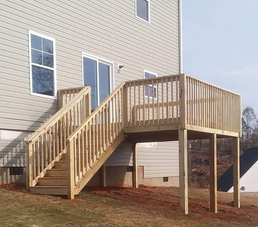 A wooden deck with stairs leading up to it in front of a house