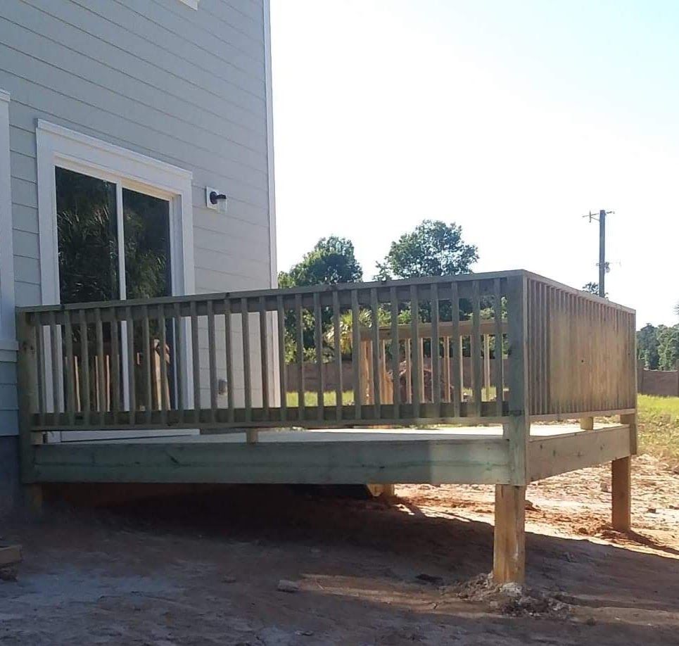 A wooden deck with a railing in front of a house