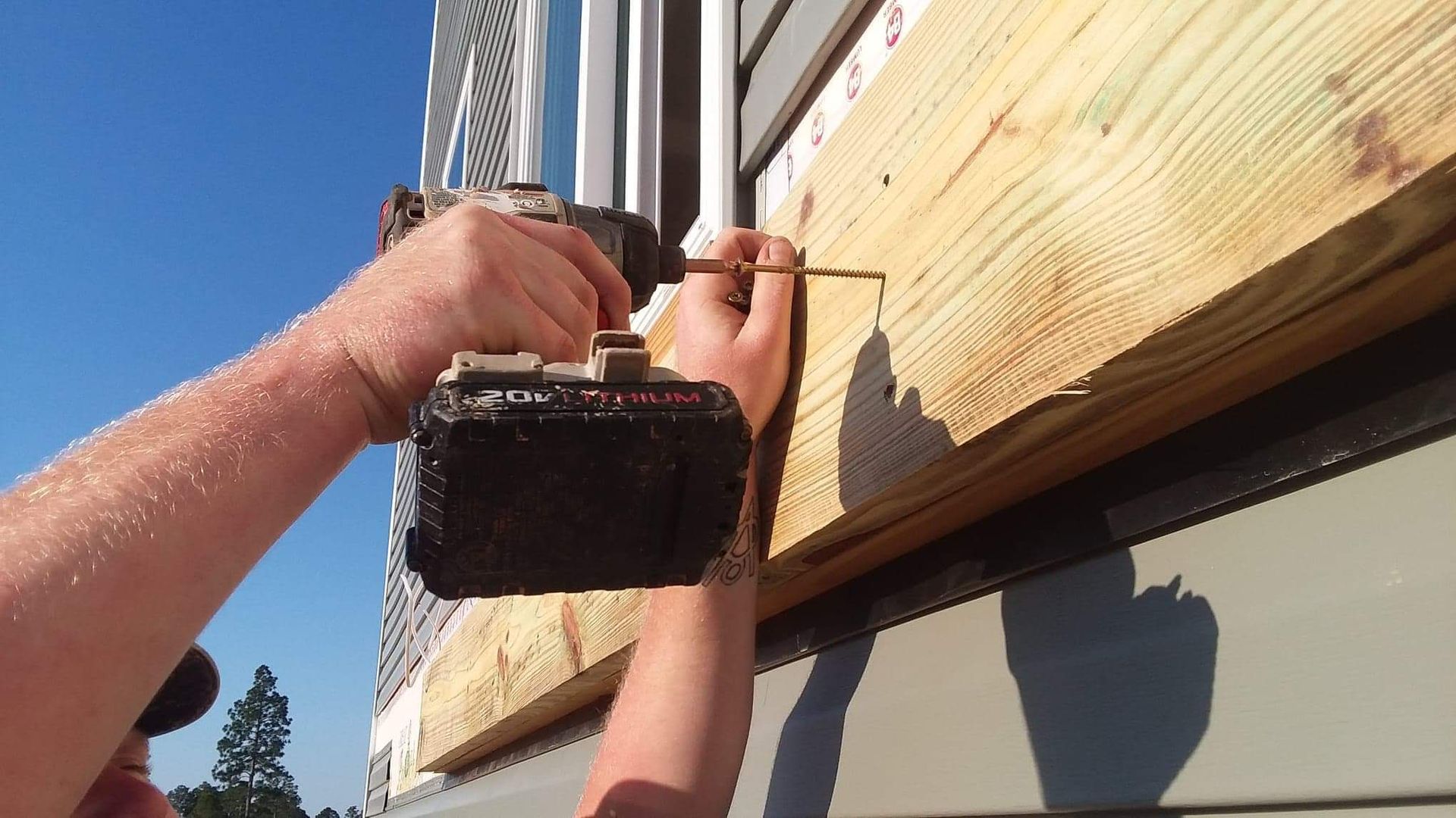 A man is using a drill on a piece of wood