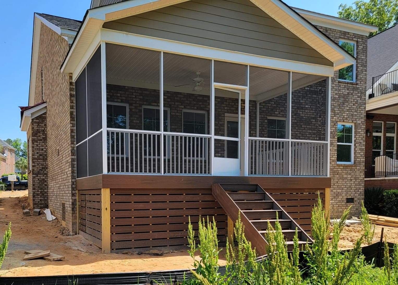 A screened in porch is being built on the side of a brick house.