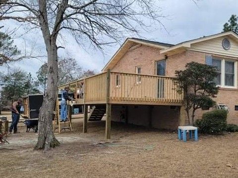 A wooden deck is being built in front of a brick house.
