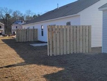 A wooden fence is in the backyard of a house.
