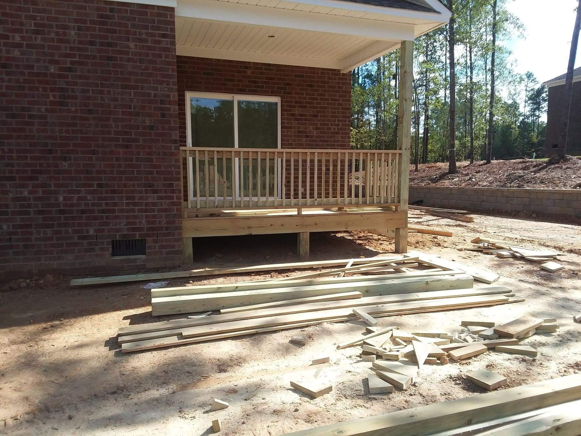 A wooden deck is being built in front of a brick house