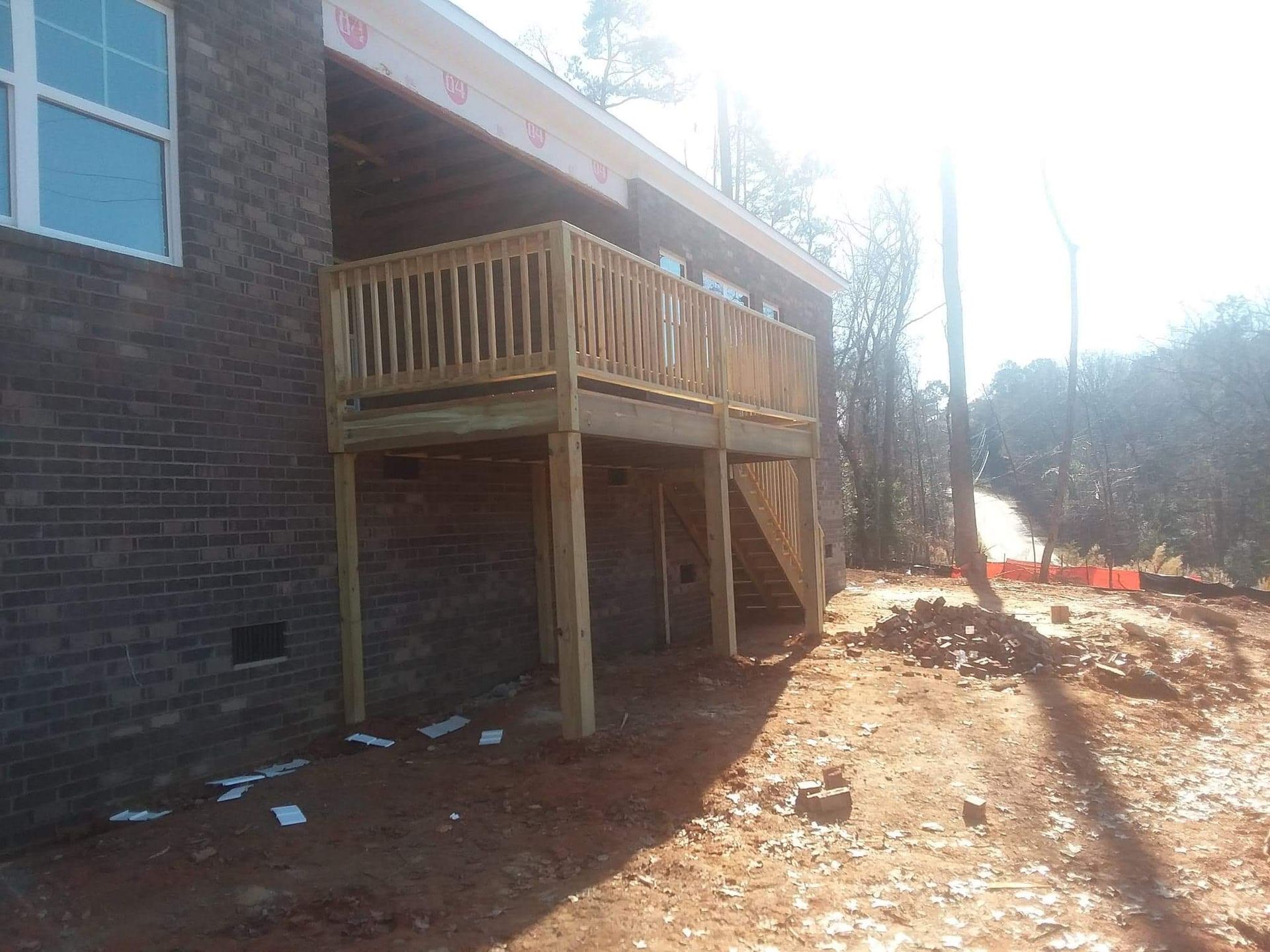 A wooden deck is being built on the side of a brick house.