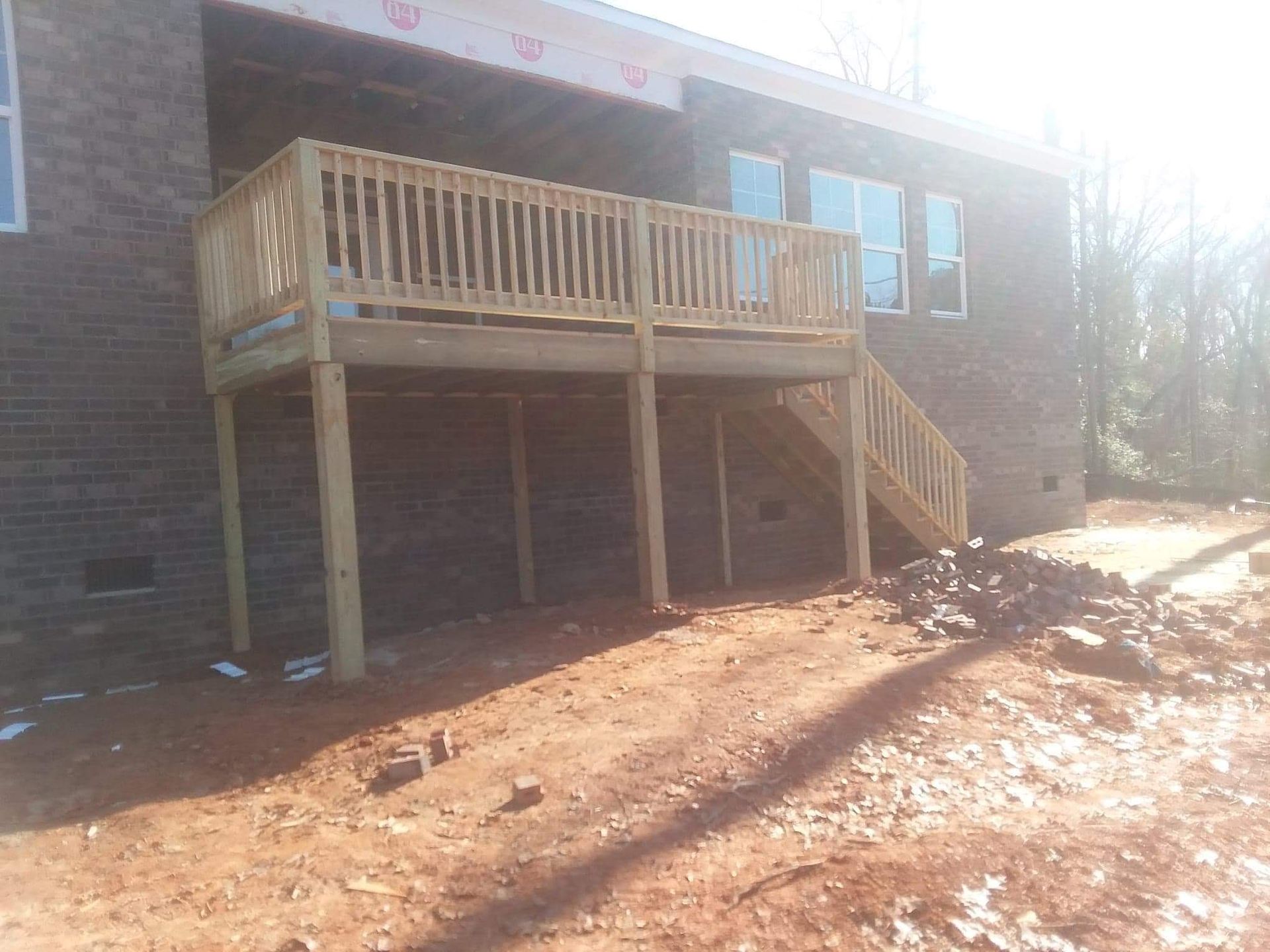A wooden deck with stairs is in front of a brick building.